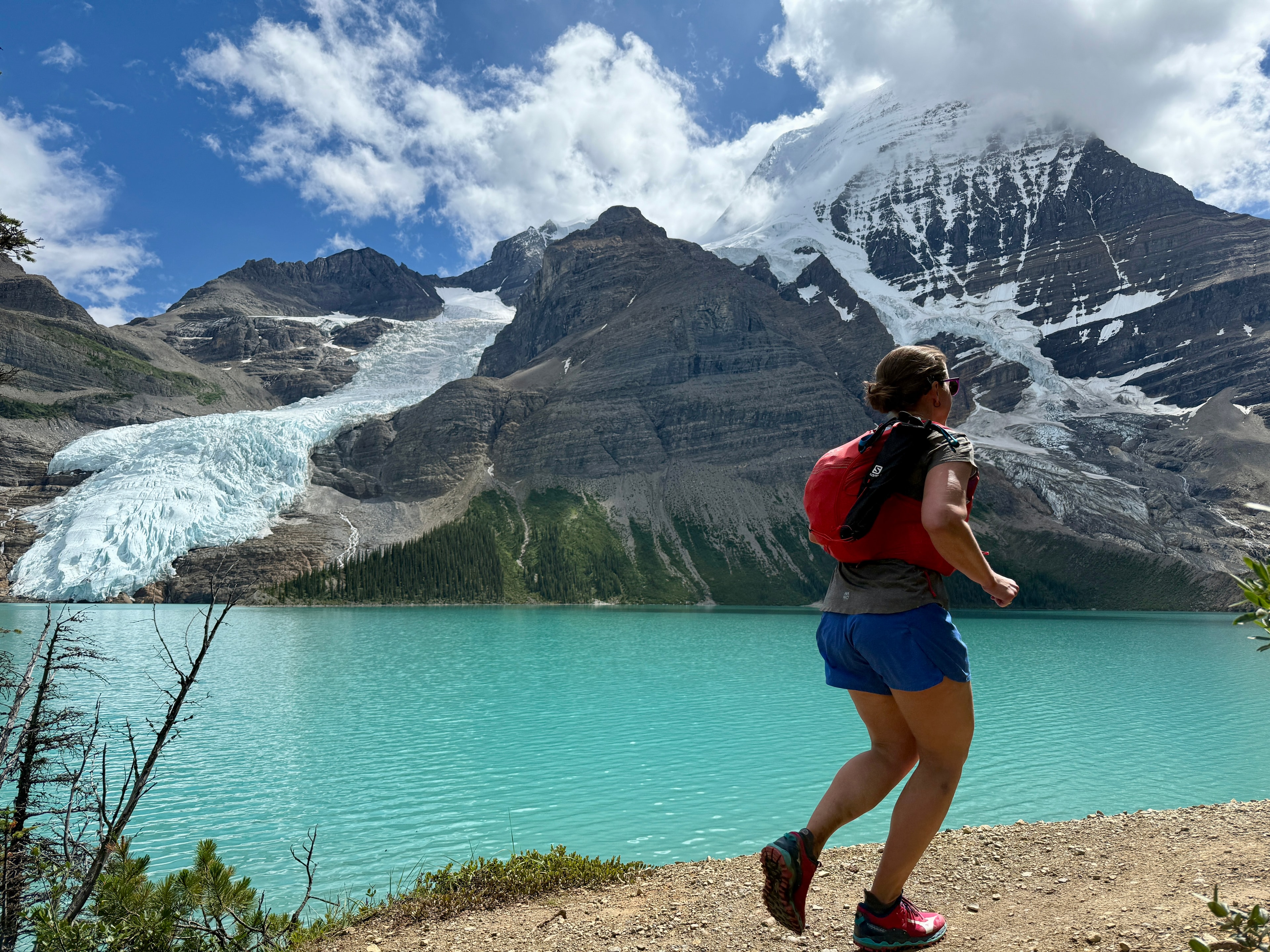 Runner beside a glacier-fed turquoise lake with towering peaks