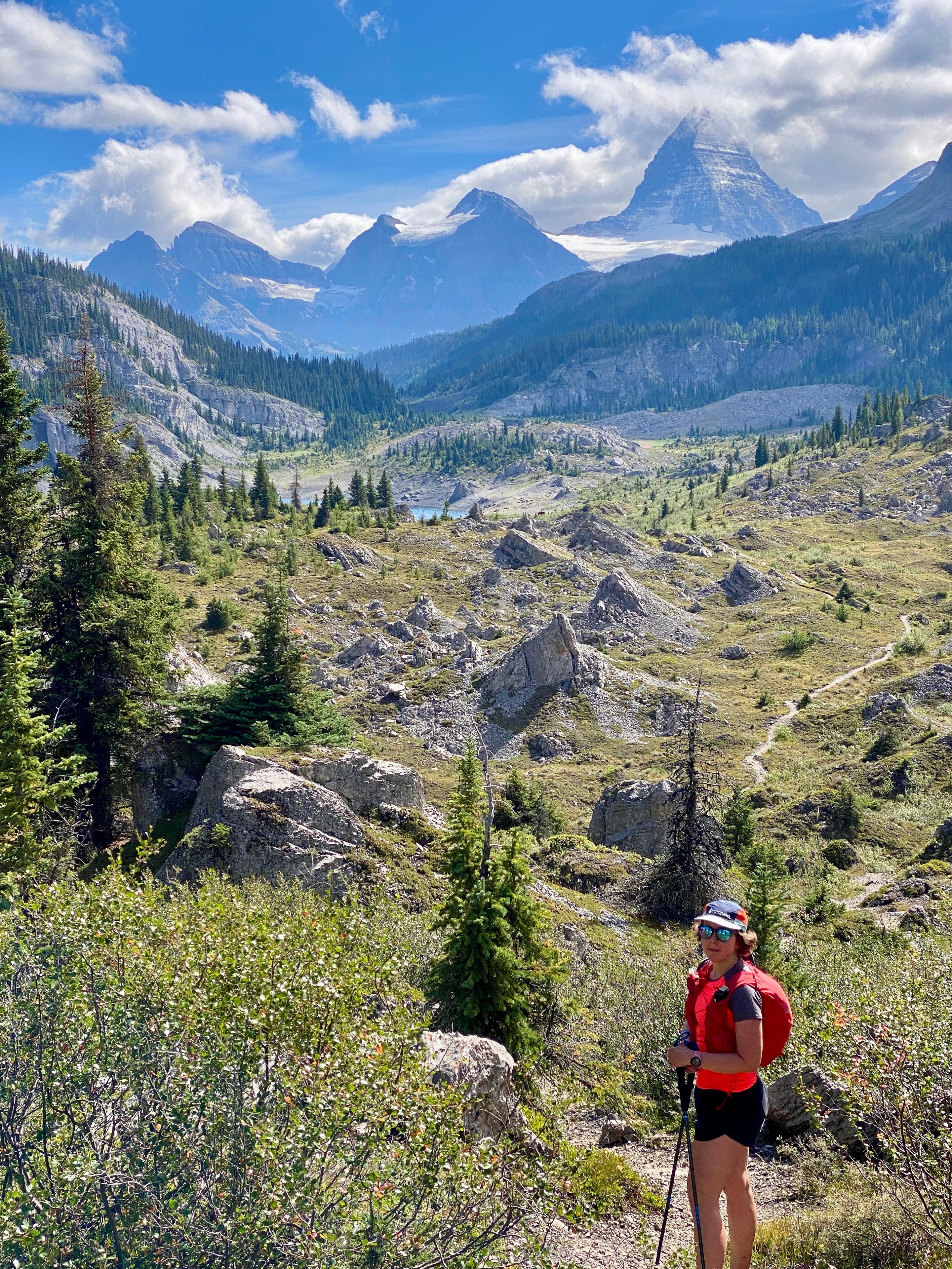 Hiker overlooking a rocky alpine valley with Mount Assiniboine in the distance
